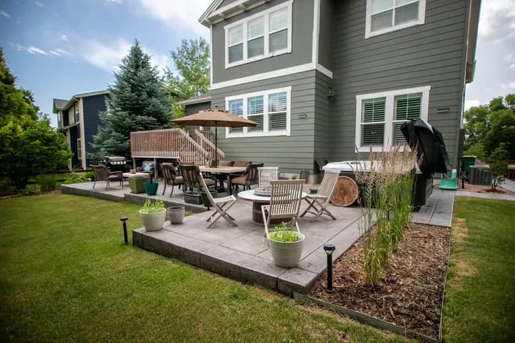 Sorensen backyard in Westminster: two-tier stamped concrete patio with dining zone, lounge seating, hot tub, and lawn