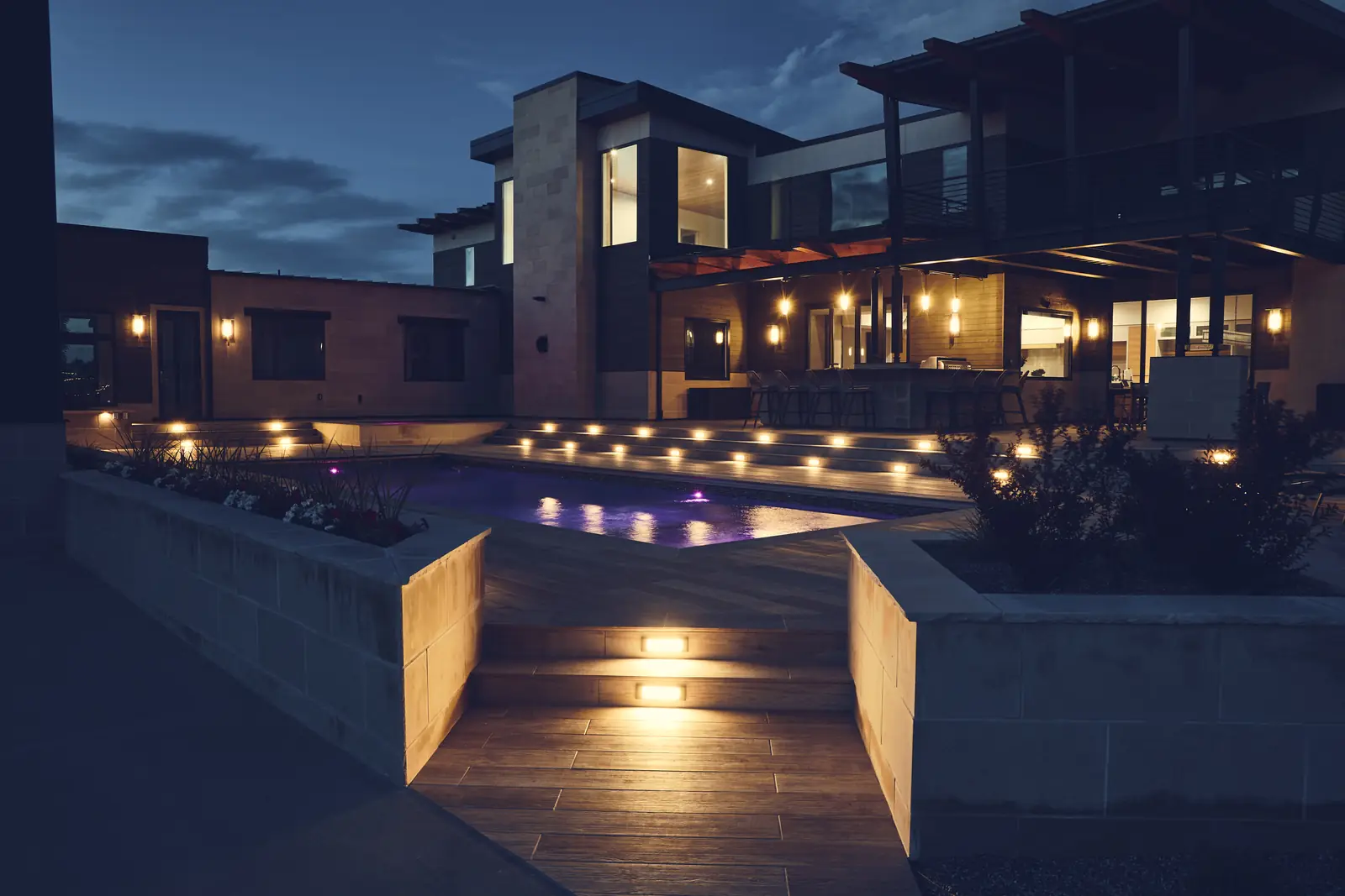 Twilight view of the finished custom pool with deck steps and landscape lighting