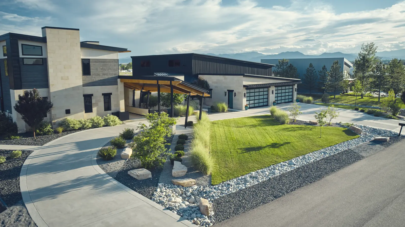 Modern Colorado home with covered outdoor living area, curved driveway, and designed landscape beds