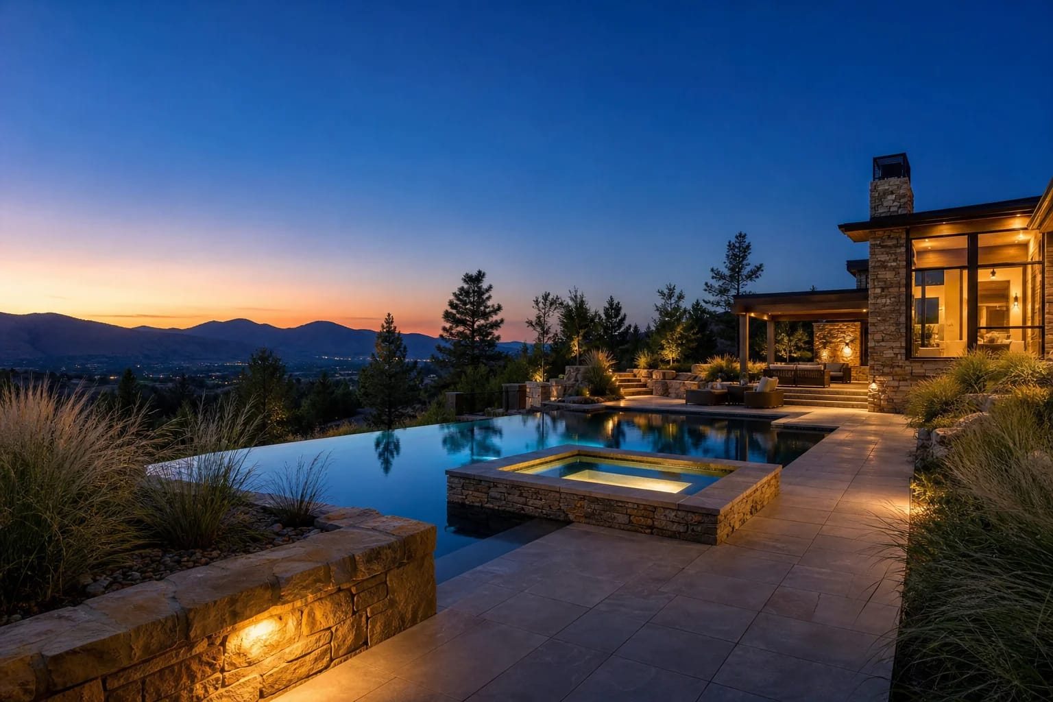 Twilight infinity-edge pool with integrated spa, porcelain deck, and foothills sky on a Colorado luxury estate