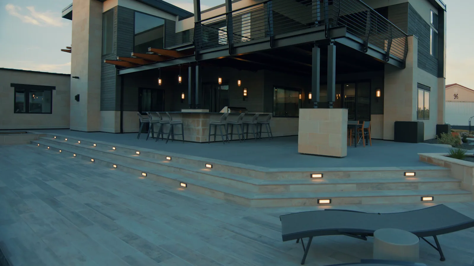 Porcelain paver deck with lit steps and the outdoor bar at dusk, the Johnson Estate in Colorado
